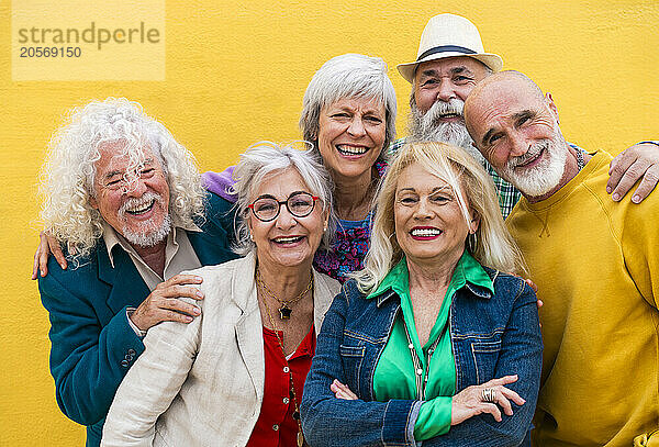 Cheerful senior friends in front of yellow wall