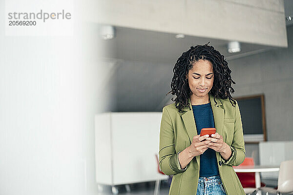 Young beautiful businesswoman using smart phone standing at office