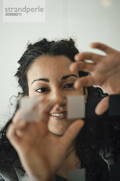 Smiling businesswoman touching glass wall