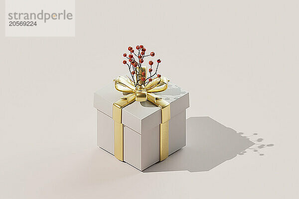 Elegant gift box wrapped in golden ribbon with artificial cherries kept over colored background