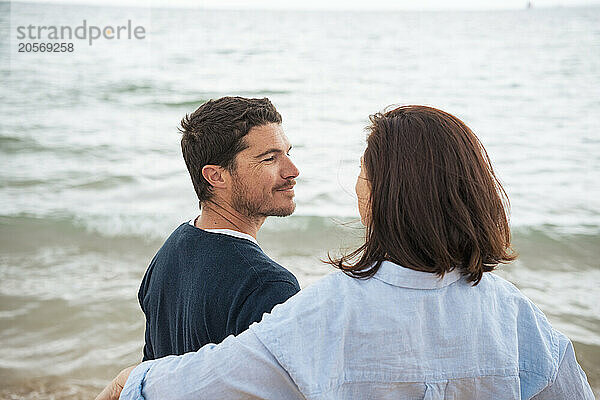 Smiling man with woman in front of sea at beach