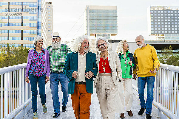 Retired men and women walking together on footbridge in city