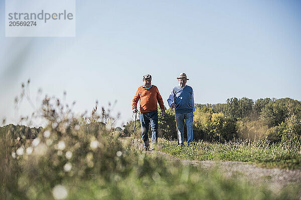 Active seniors walking on dirt road at field