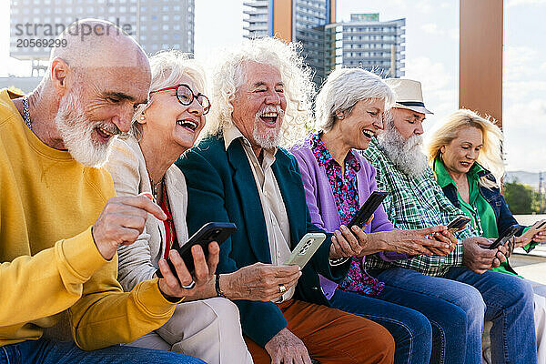 Cheerful men and women using smart phones sitting together