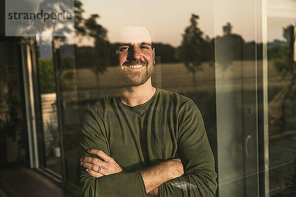 Happy man with arms crossed seen through glass