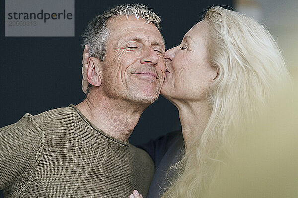 Blond woman kissing man with eyes closed