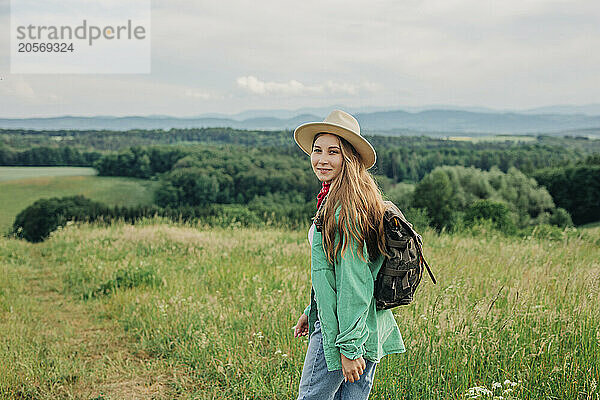 Smiling young woman with backpack hiking on mountain in Poland