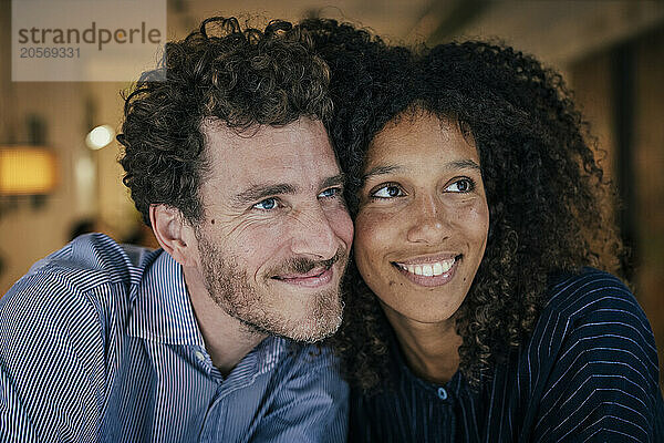 Cheerful couple with cheek to cheek sitting in cafe