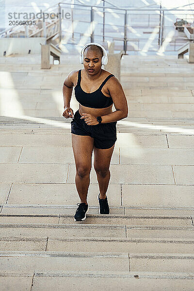 Sporty muscular woman jogging on steps