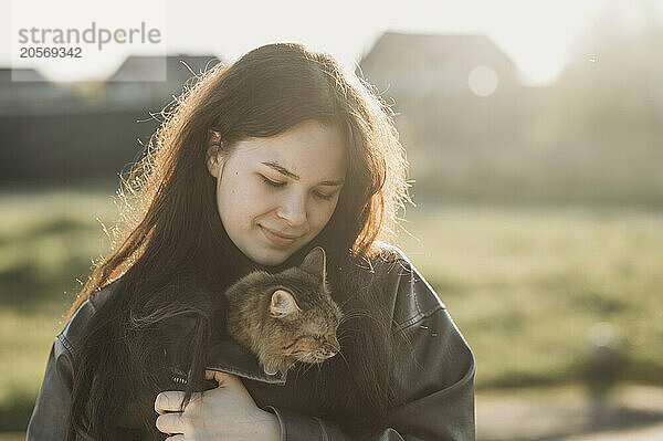 Teenage girl with brown hair holding cat