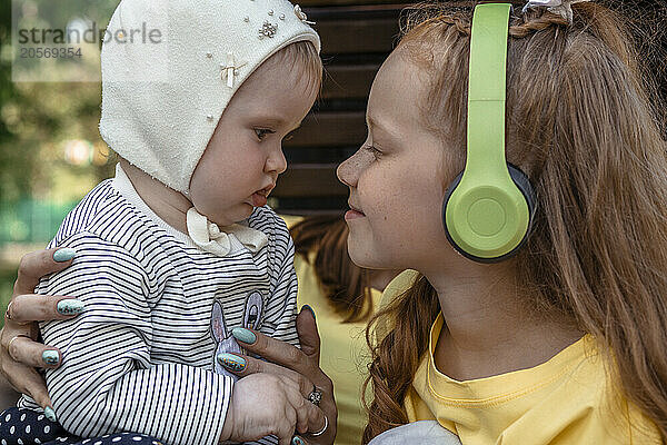 Smiling girl wearing wireless headphones and embracing sister