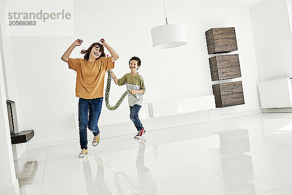 Happy siblings running and playing in empty room of new apartment