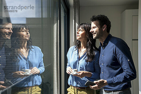 Happy businessman and businesswoman looking through glass window