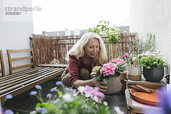 Blond senior woman with flower pot at garden