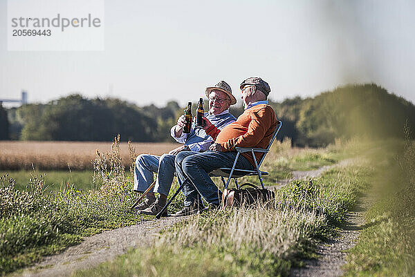 Friends laughing and enjoying drink at field