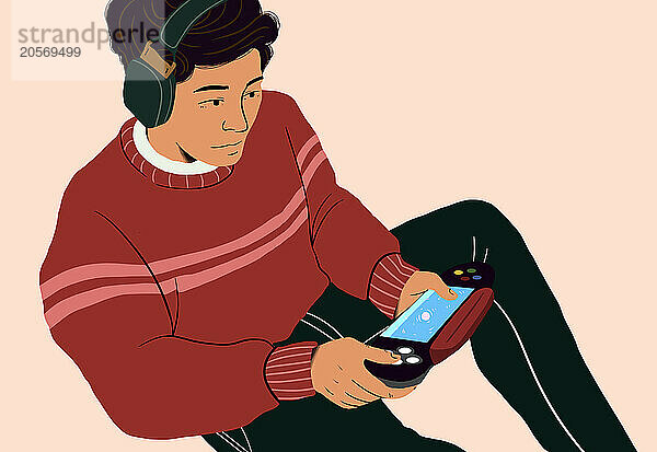 Teenage boy with headphones playing on smartphone with gaming controller