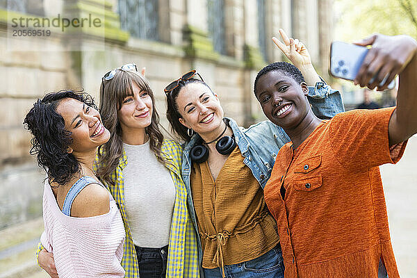 Smiling woman taking selfie with friends through smart phone