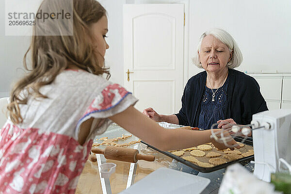 Granddaughter preparing cookies with grandmother at home