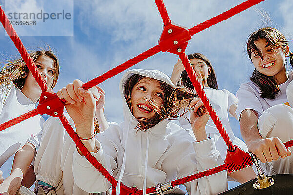 Teenage friends enjoying on jungle gym at playground