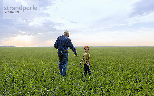 Senior man with grandson standing on grass