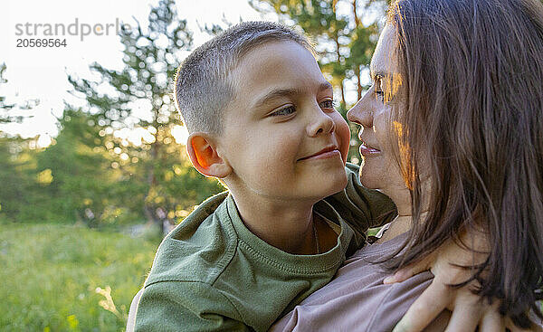 A boy hugs his mother in the park.