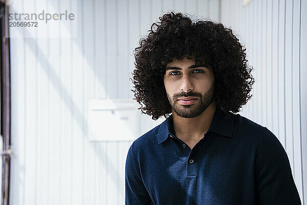 Confident businessman with curly hair and stubble at workplace