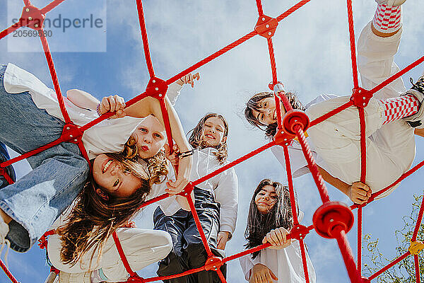 Happy teenage friends playing on jungle gym at park