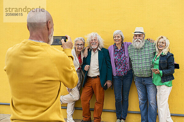 Man photographing elderly friends through smart phone