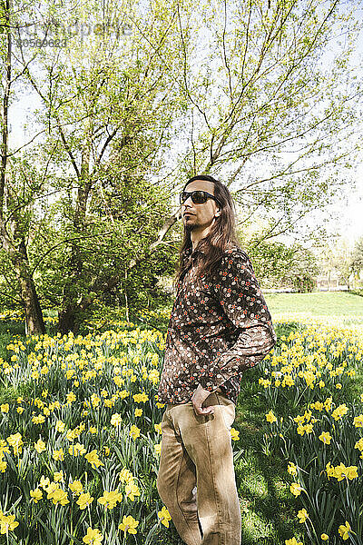 Man wearing sunglasses standing amidst daffodil flowers at meadow