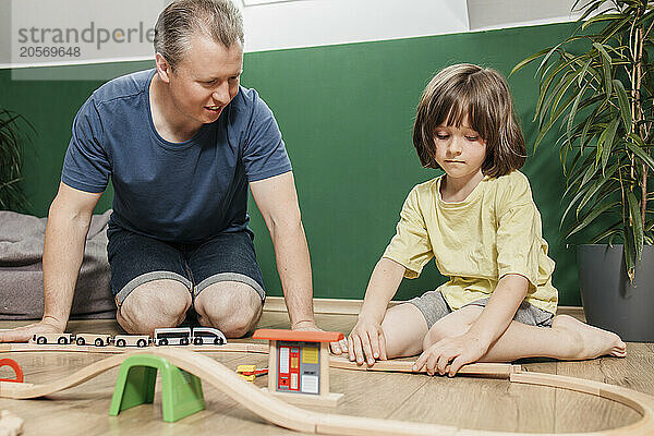 Son building toy train set with father at home