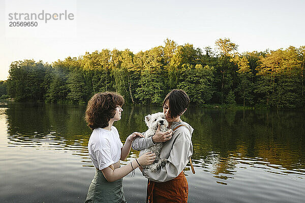 Mother and daughter with dog standing near river