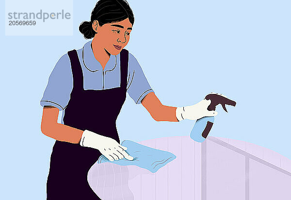 Woman in maid uniform cleaning glass table with cloth and spray bottle