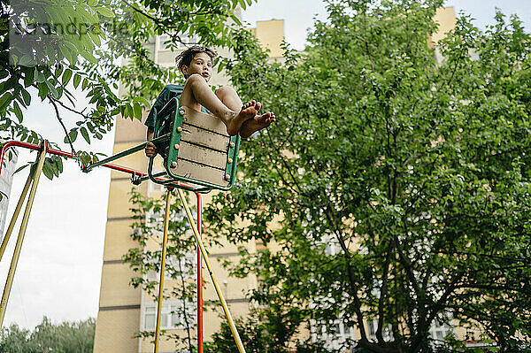 Boy swinging on swing in playground