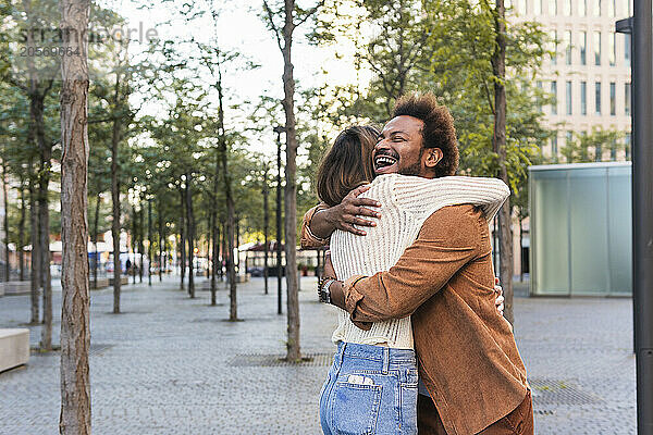 Happy man embracing girlfriend on footpath