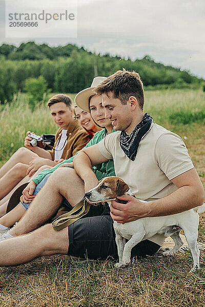 Young couples sitting with dog on mountain