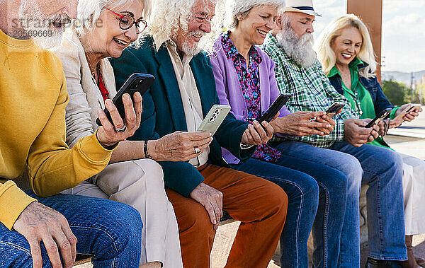 Smiling women and men using smart phones sitting together