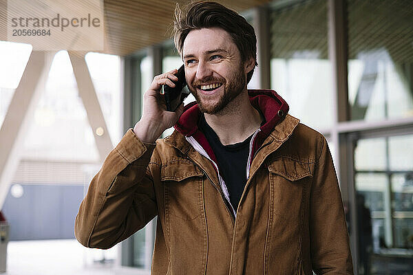 Happy man talking on smart phone in public building