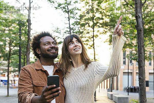 Smiling woman pointing to man with smart phone