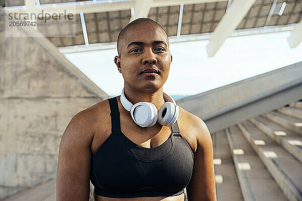 Confident muscular woman with headphones on steps