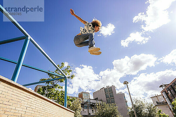 Man jumping under cloudy sky