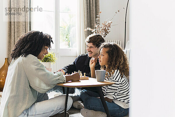 Parents sitting in livingroom teaching daughter to play chess