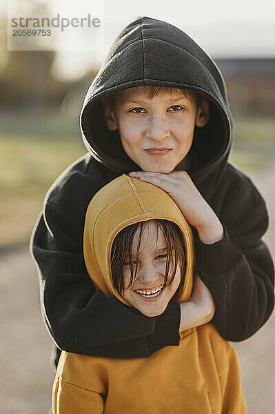 Smiling boy embracing brother wearing hoodie