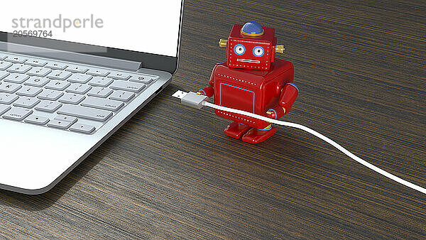 Red robot with cable by laptop on table