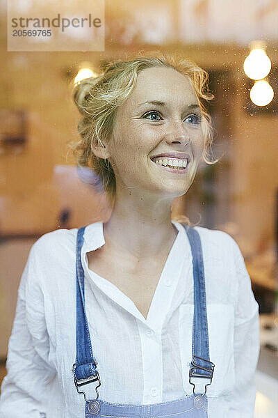 Smiling young woman seen through glass in cafe