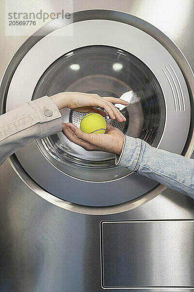 Hands of couple holding tennis ball in laundromat