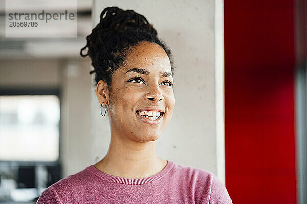 Happy businesswoman standing in front of column at office