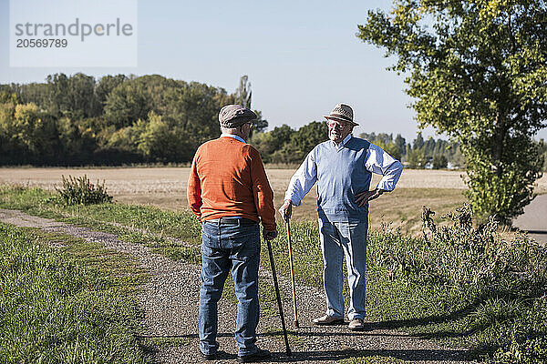 Friends talking in middle of road near field