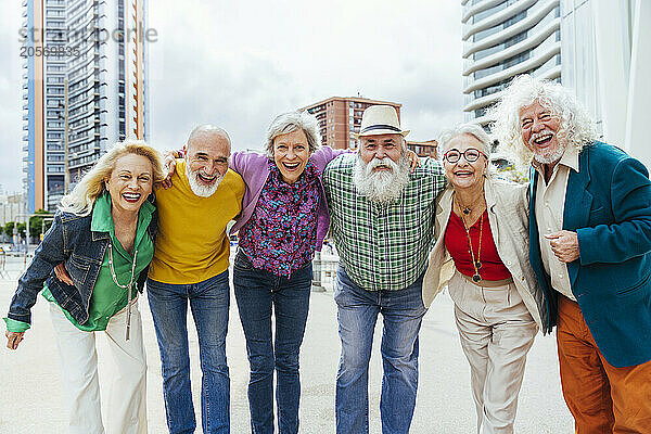 Elderly friends with hands on shoulders enjoying in city