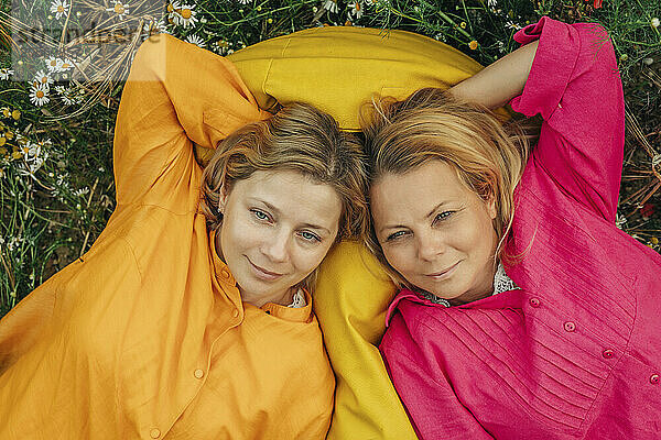 Happy sisters lying together on yellow bean bag