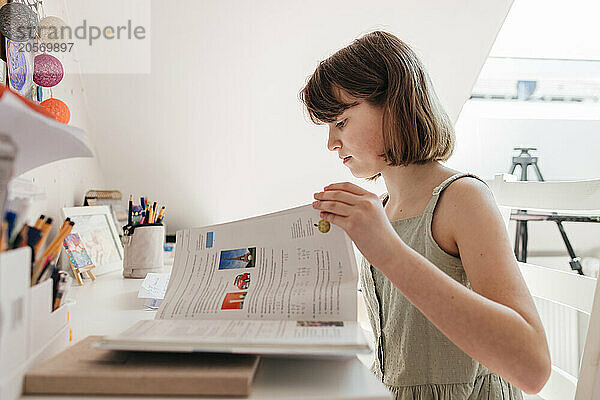 Girl reading textbook and doing homework at home